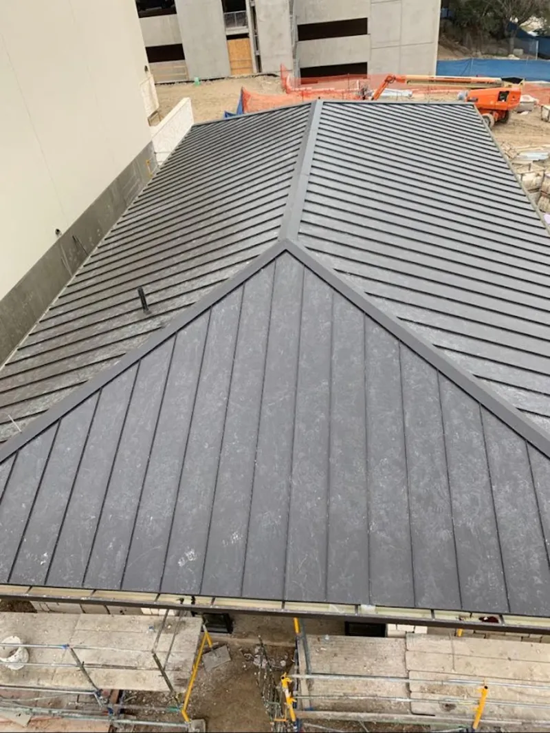 Commercial metal roof construction with crane equipment in Delta